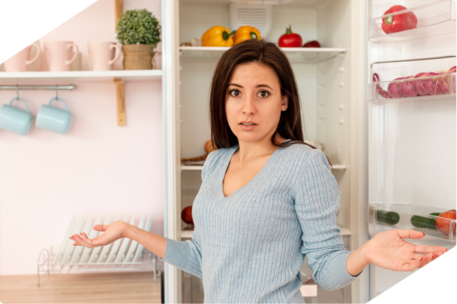 Woman looking confused in front of an open refrigerator, unsure of what to do with an empty fridge.