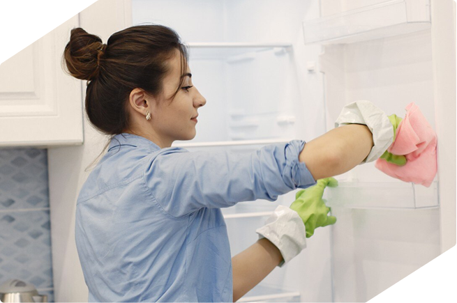 Woman cleaning the inside of a fridge with gloves, promoting hygiene and maintenance for optimal refrigerator performance.