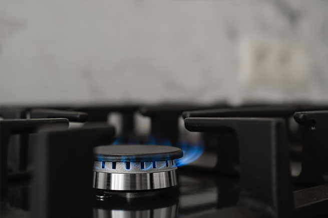 Close-up of a gas stove burner with a blue flame, perfect for cooking with precision and control.