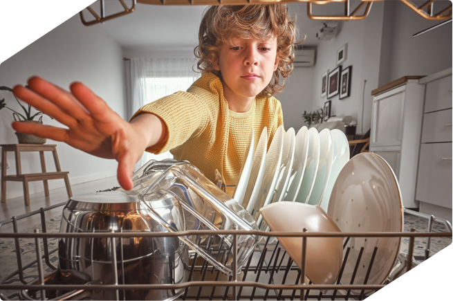 Young boy exploring a loaded dishwasher.