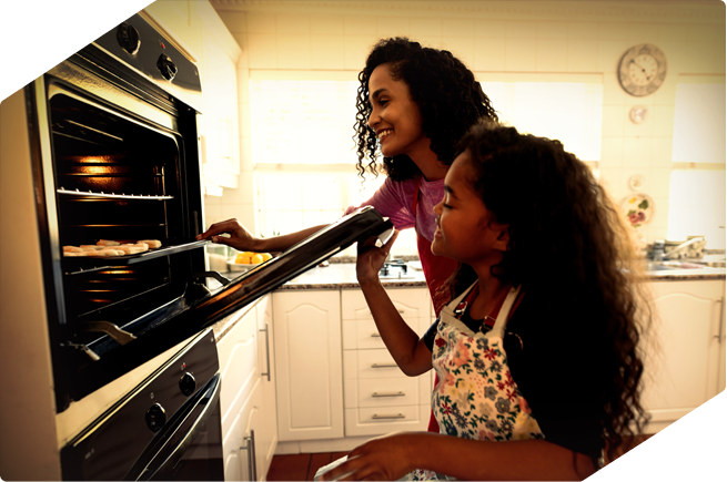 Mother and daughter baking holiday treats together, showcasing tips to extend the life of your oven during the festive season