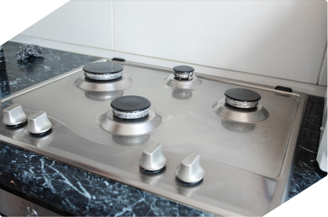 tainless steel gas stove with a sleek, minimalist design, featuring four burners on a black marble countertop.