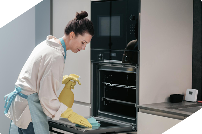 Woman cleaning an oven using natural cleaners to achieve a sparkling result without harsh chemicals.