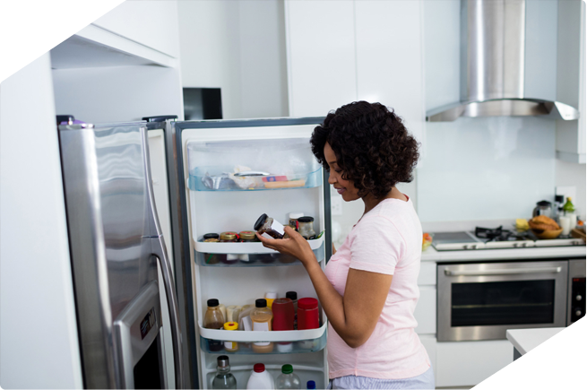 A woman organizing her refrigerator to ensure food stays fresh and neatly stored.