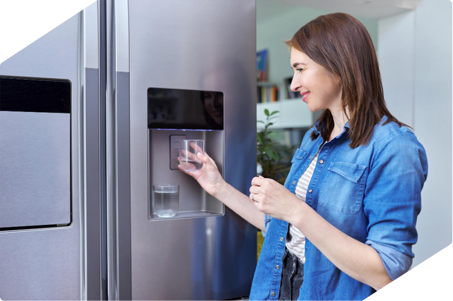 Woman using a refrigerator water dispenser, showcasing the convenience of modern appliances for easy water access.