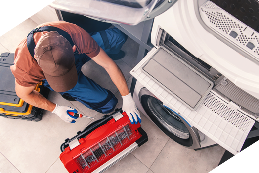 Technician repairing a dryer with a toolbox, providing expert appliance repair service.