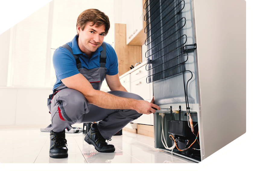 Technician repairing a refrigerator, showcasing professional appliance repair service.